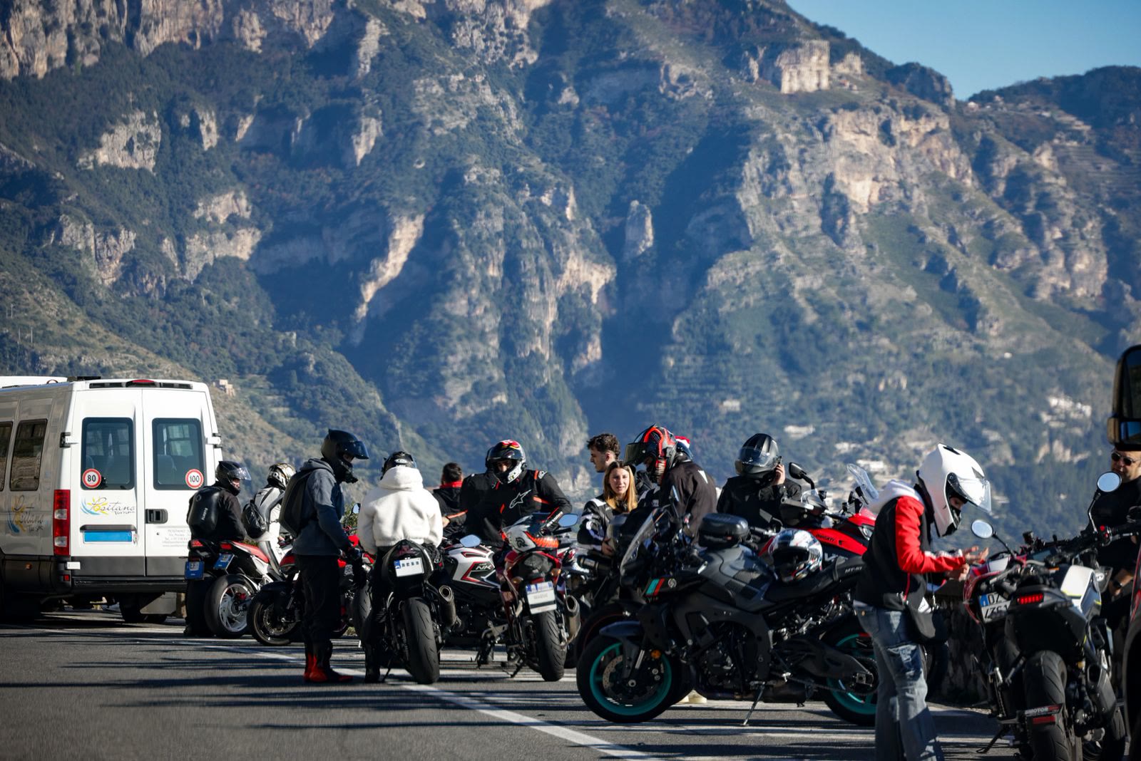 Un gruppo numeroso di motociclisti fermo su un piazzale di montagna