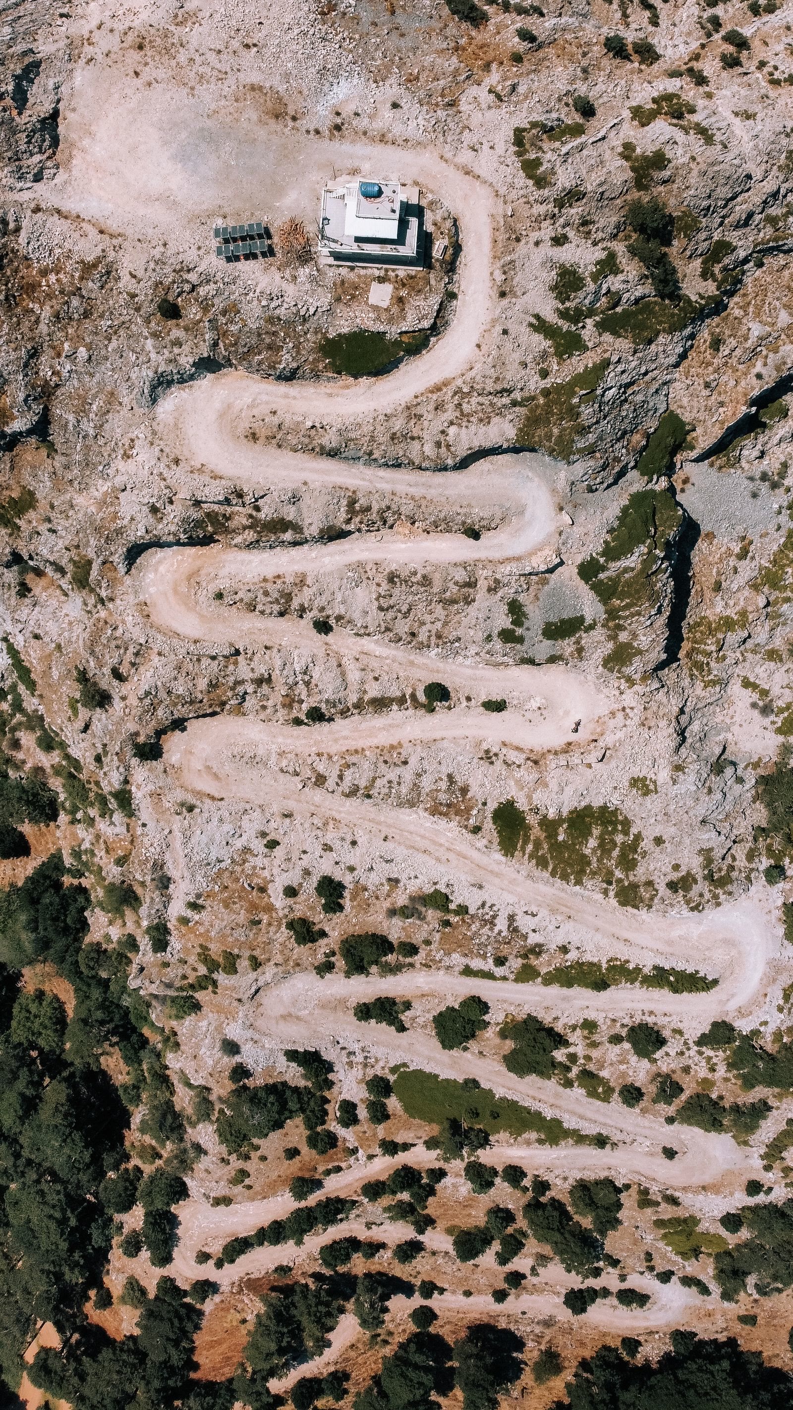 Una strada sterrata a tornanti vista dall'alto, su un pendio di roccia chiara